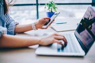 Foto: Frau mit Smartphone und Laptop